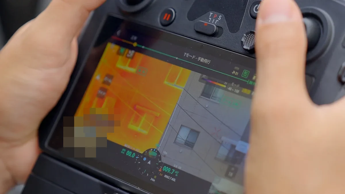 ドローンの送信機に映る外壁の赤外線画像。タイルの浮きや漏水が周囲との温度差として色で現れている